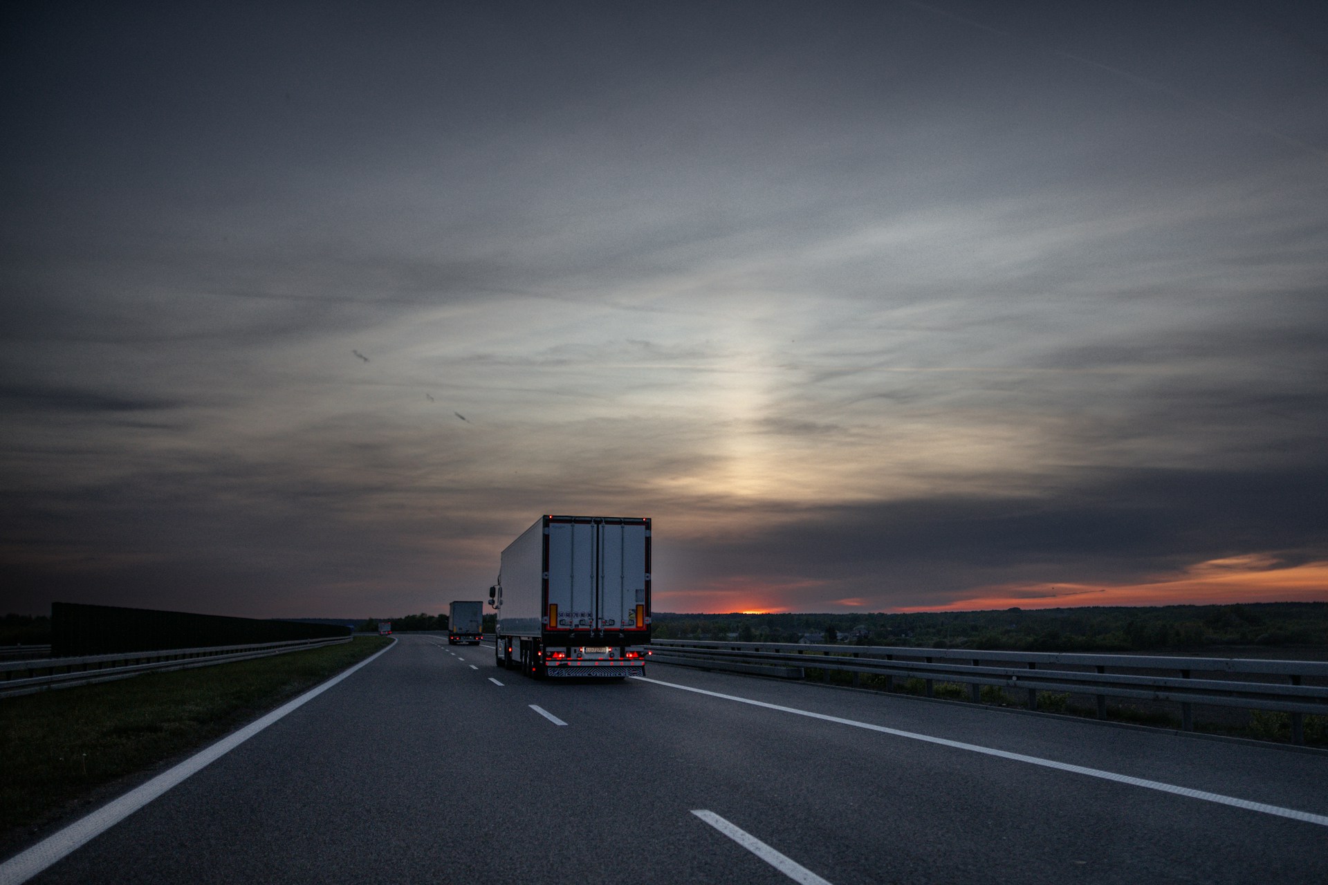 Freight trucks on an open highway at dusk